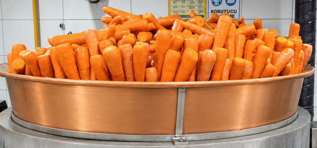 Fresh carrots piled in a copper cauldron at the Adana workshop